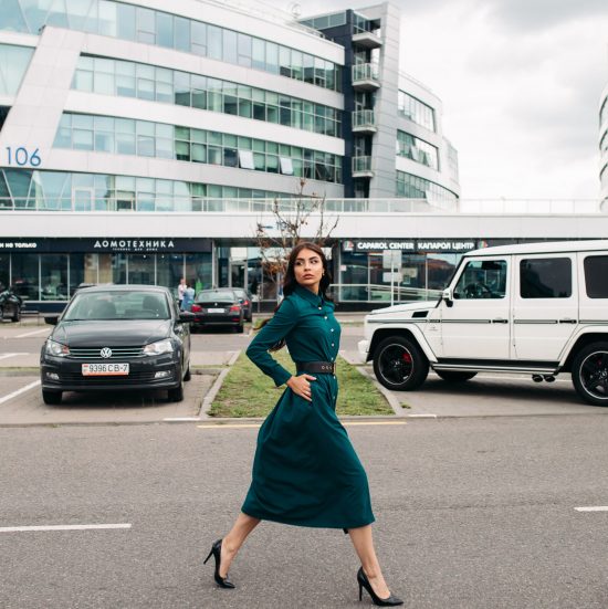 Full length photo of attractive young woman with long hair walking on street in the city while looking away. City lifestyle